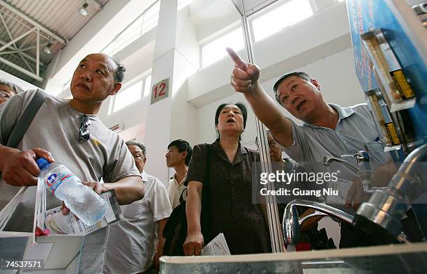 Vendor introduces his water saving faucet product during the '2007 Beijing international energy conservation and environment protection exhibition'...