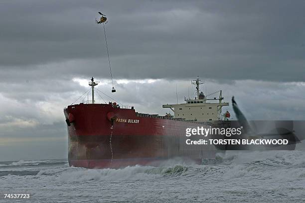 Helicopter lowers salvage equipment to the deck of the 30,000-tonne bulk coal carrier 'Pasha Bulker' which ran aground in wild seas off a beach in...