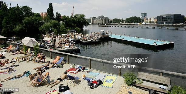 People enjoy a swim in a swimming pool as others relax on a beach set up on the river Spree in Berlin 11 June 2007, are unusually high in the German...
