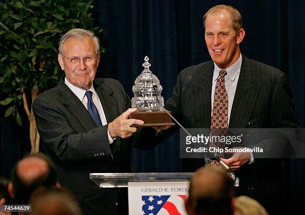 Former Ford and Bush Administration Secretary of Defense Donald Rumsfeld accepts a trophy from Steve Ford, son of former U.S. President Gerald R....