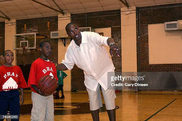 Caron Butler of the Washington Wizards teaches basketball shooting skills to children during the Caron Butler 3D Youth Basketball Camp on June 11,...