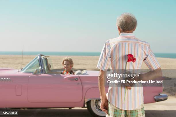 senior man surprising wife with flower - man giving flowers foto e immagini stock