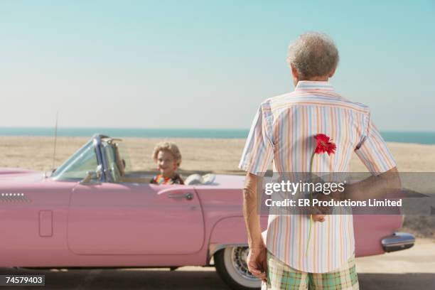 senior man surprising wife with flower - liason stock pictures, royalty-free photos & images