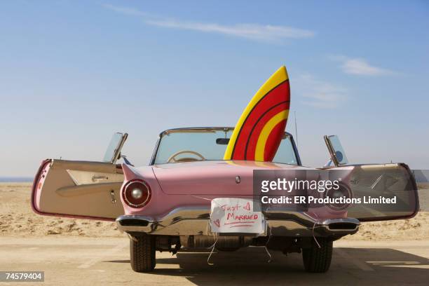 convertible car with just married sign and surfboard - newlywed fotografías e imágenes de stock