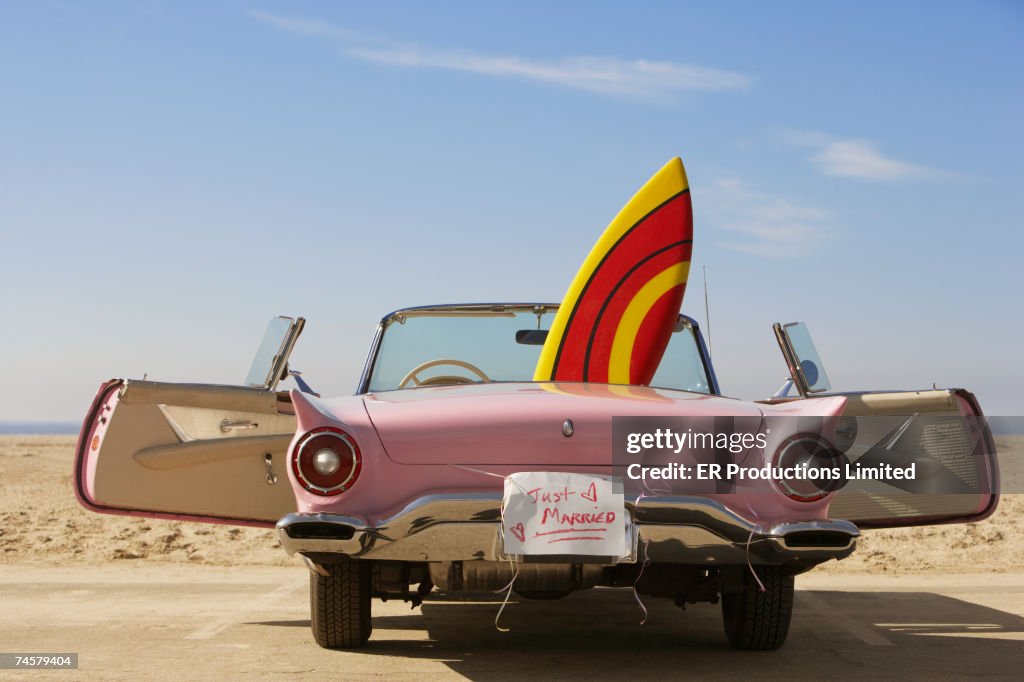 Convertible car with Just Married sign and surfboard