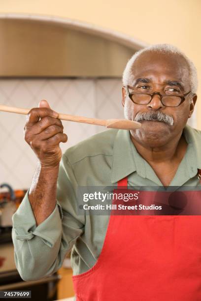 senior african man tasting from wooden spoon - solo un uomo anziano foto e immagini stock