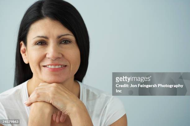 hispanic woman resting chin on hands - 40 49 years stock pictures, royalty-free photos & images