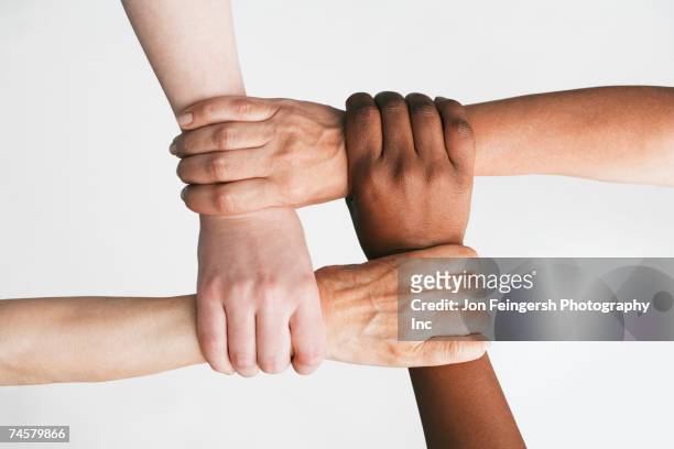 multi-ethnic women holding wrists - four people stock-fotos und bilder
