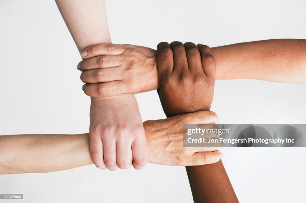 Multi-ethnic women holding wrists