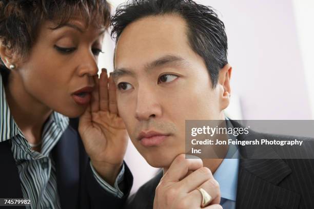 businesswoman telling secret to businessman - こっそり ストックフォトと画像