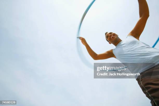 hispanic man playing with hula hoop - gymnastikreifen stock-fotos und bilder