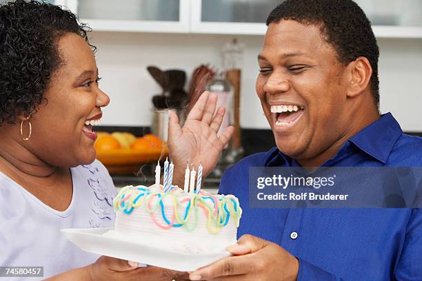 african couple celebrating birthday - man giving cake candle stock pictures, royalty-free photos & images