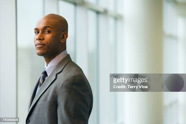african businessman standing next to window - financial strength stock pictures, royalty-free photos & images