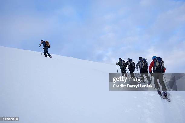 group of people climbing in snow, one leading, low angle view, rear view - people climbing walking mountain group stock pictures, royalty-free photos & images