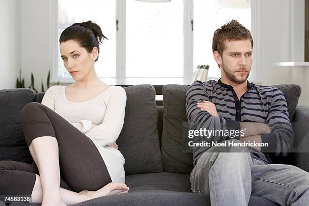 couple sitting on sofa with arms folded, looking angry - couple ignore stock-fotos und bilder