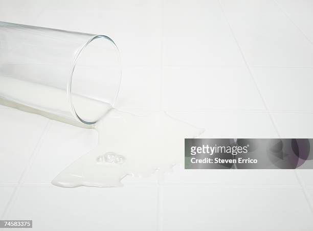 glass of spilt milk on white background, close-up - spilt milk stock-fotos und bilder