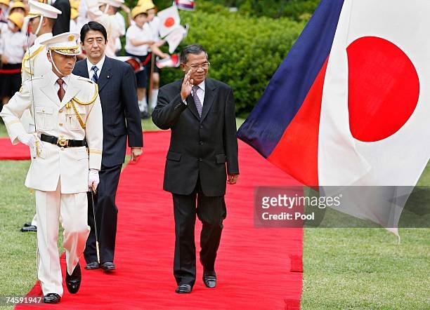 Accompanied by his Japanese counterpart Shinzo Abe , Cambodian Prime Minister Hun Sen waves to Japanese honor guards during a welcoming ceremony at...