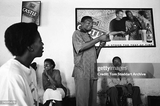 Peer educator demonstrates how to put on a condom inside a shebeen where miners from the Lonmin platinum mine drink beer, South Africa, June 2003....