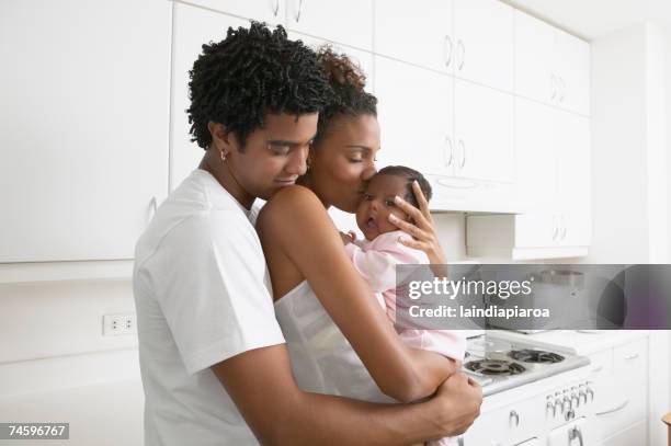 african parents hugging baby in kitchen - baby father hug side stock-fotos und bilder