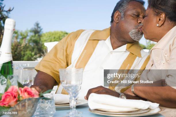 senior african couple kissing outdoors - large dinner party stock pictures, royalty-free photos & images