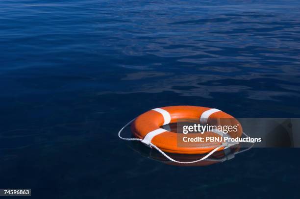 round life preserver floating in water - befreiung stock-fotos und bilder