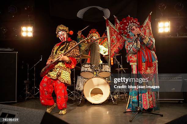 two actors and an actress dressed as traditional beijing opera characters play rock and roll together on stage. - masked musicians stock pictures, royalty-free photos & images