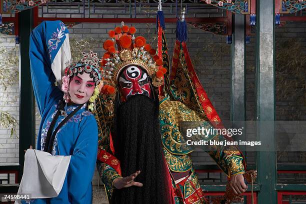 an actress dressed as a traditional beijing opera princess and an actor dressed as a army general strike martial art poses in an outdoor pavilion. - chinese mask stockfoto's en -beelden