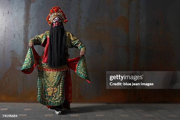 actor dressed as a traditional beijing opera army general dances in front of an industrial rusting steel wall. - beijing opera stock pictures, royalty-free photos & images