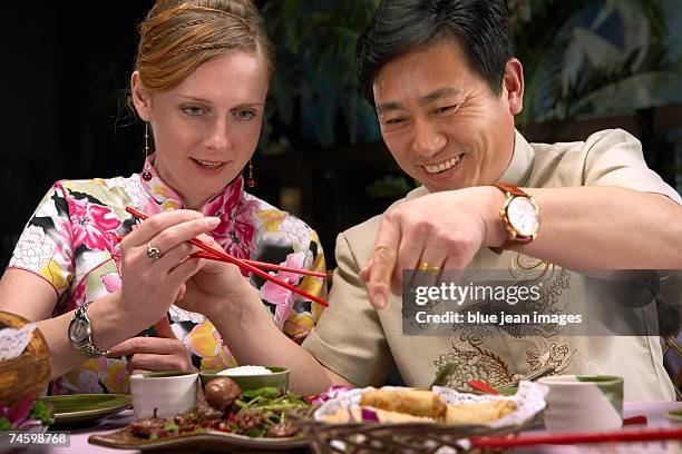 man and woman eat spring rolls at a chinese restaurant. - waitress booth stock pictures, royalty-free photos & images