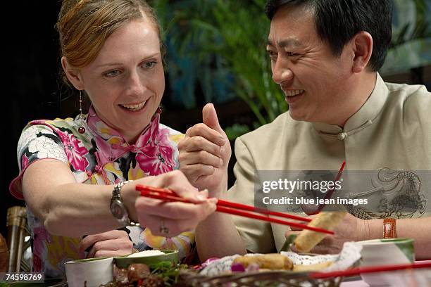 woman picks up a spring roll at a chinese restaurant. - waitress booth stock pictures, royalty-free photos & images