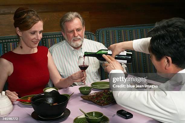 waiter pours wine for woman at a chinese restaurant. - waitress booth stock pictures, royalty-free photos & images