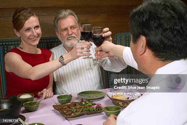 three people toast at a chinese restaurant. - waitress booth stock pictures, royalty-free photos & images