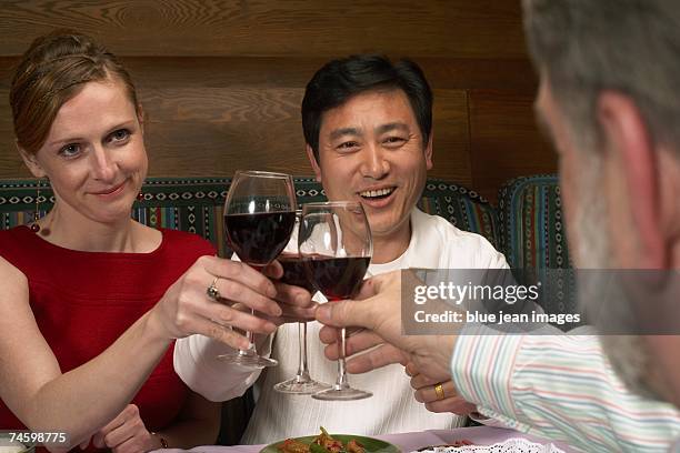 three people make a toast at a chinese restaurant. - waitress booth stock pictures, royalty-free photos & images