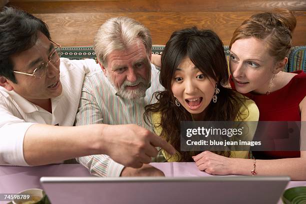 group of men and woman laugh at something on a computer screen in a chinese restaurant. - waitress booth stock pictures, royalty-free photos & images