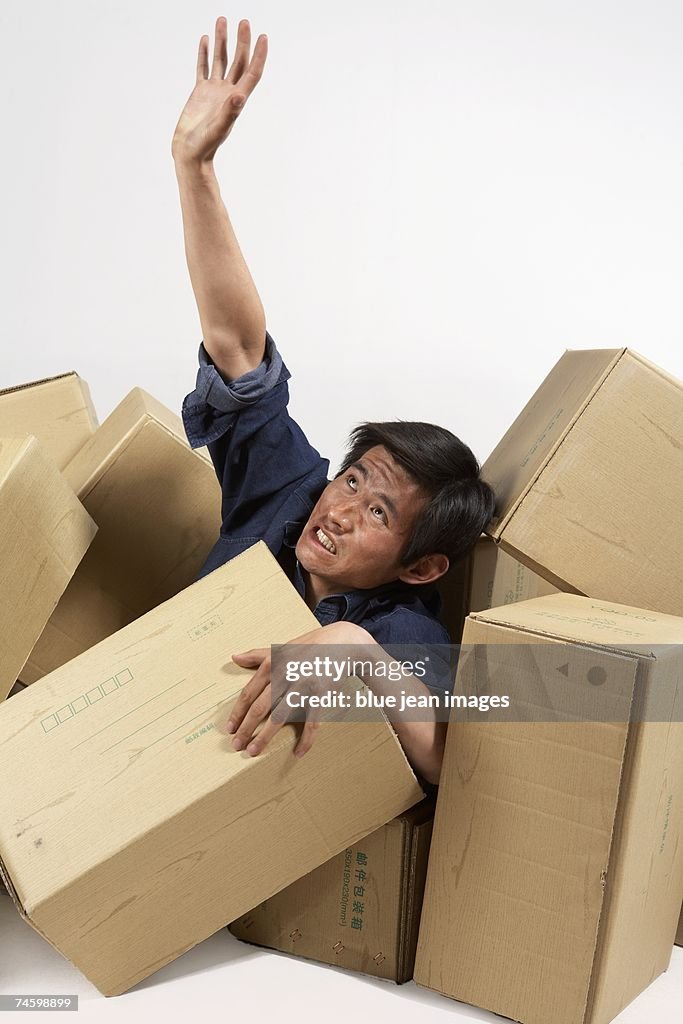Man reaches out of box pile