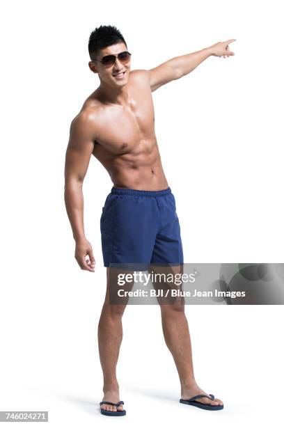 young muscular man wearing swimming trunks - badehose stock-fotos und bilder