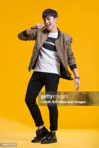 cheerful young man singing with microphone - asian singer stock pictures, royalty-free photos & images