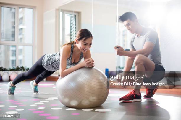 young woman working with trainer at gym - asian female bodybuilder stock-fotos und bilder