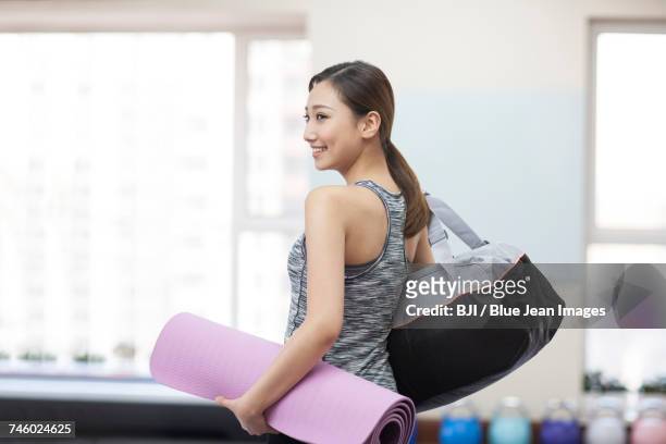 young woman with yoga mat at gym - end of life care stock pictures, royalty-free photos & images
