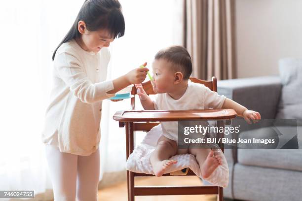 little girl feeding baby - sisters feeding stock pictures, royalty-free photos & images