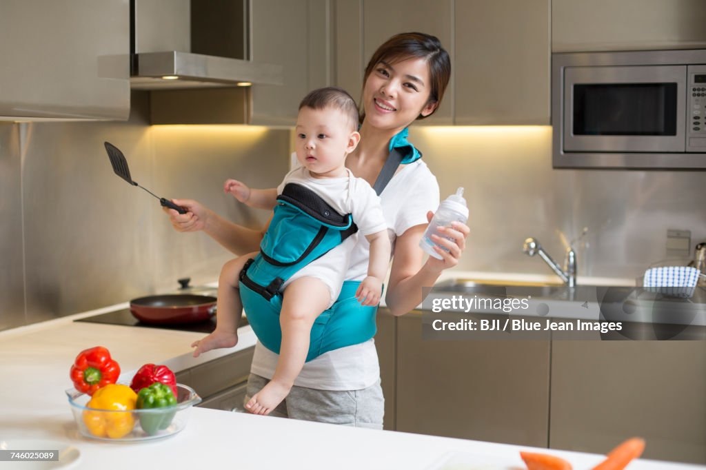 Cooking With Baby Mother Holding Baby And Cooking In The Kitchen High-Res Stock Photo ...