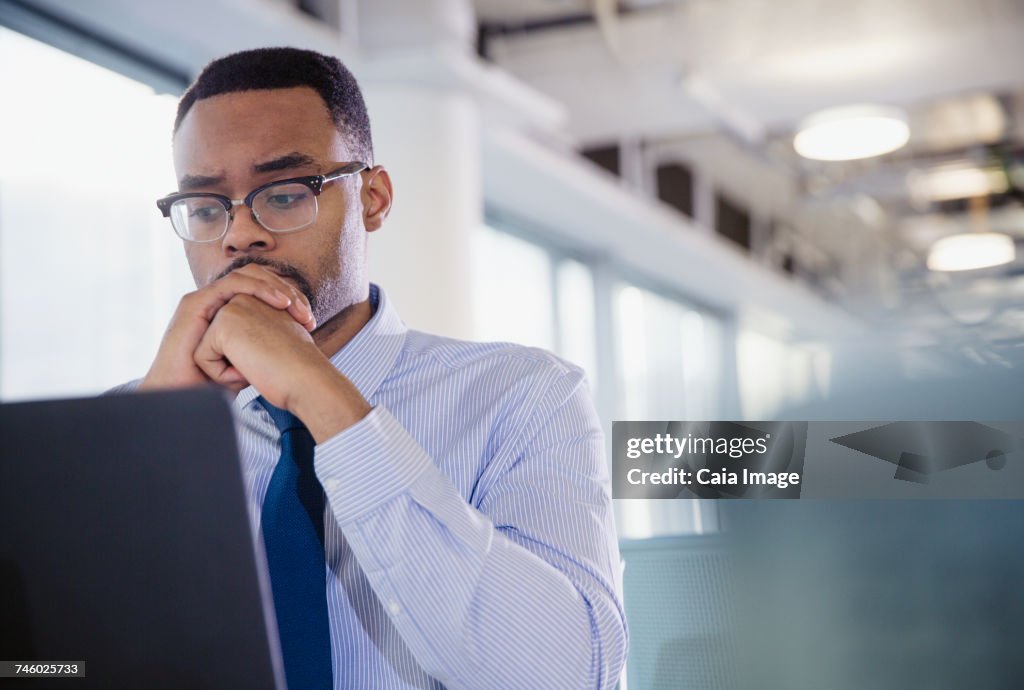 Serious, worried businessman working at laptop in office