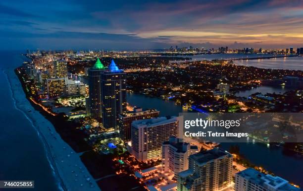 usa, florida, miami, aerial view of beach along illuminated city at dusk - urban beach stockfoto's en -beelden