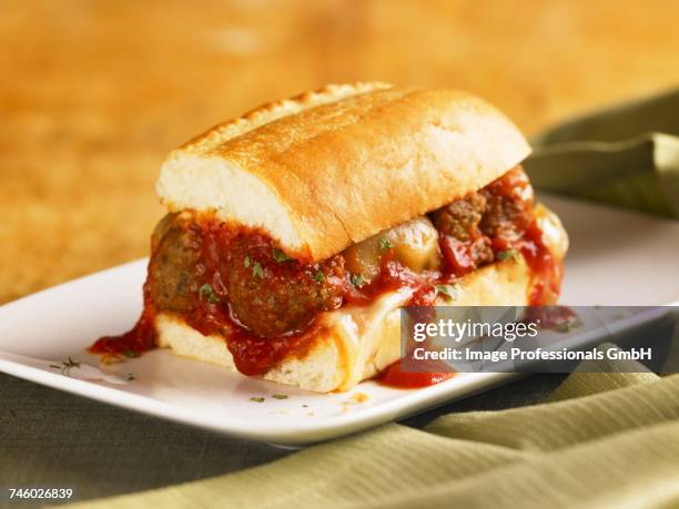 meatball sub with marinara sauce dripping down the sides; on a white plate - meatball sandwich stock pictures, royalty-free photos & images