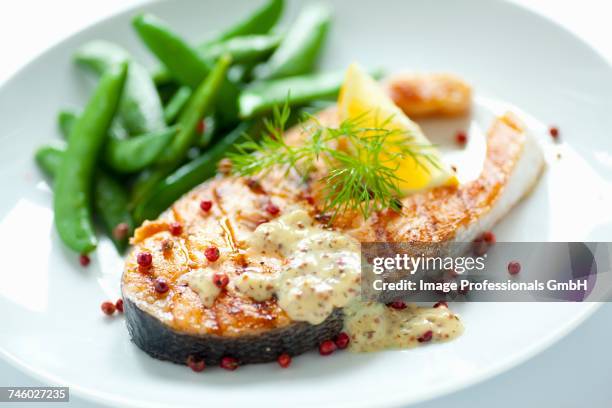 fried salmon steak with sugar snap peas, honey and mustard sauce and red peppercorns - sauce miel moutarde photos et images de collection