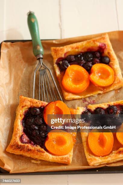 puff pastry slices with apricots and blueberries - blechkuchen stock-fotos und bilder