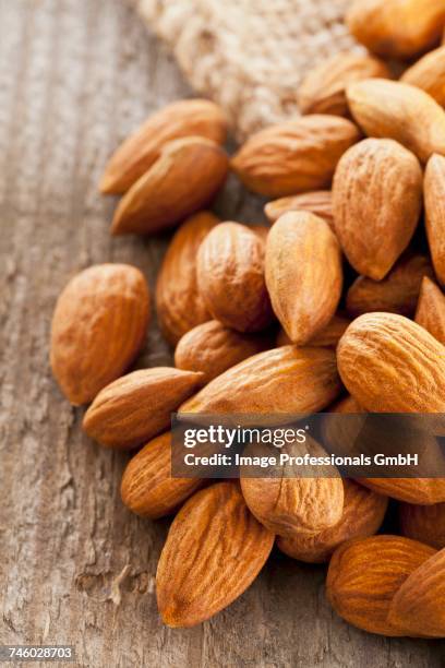 a pile of almonds on a wooden surface - wooden surface finishes foto e immagini stock