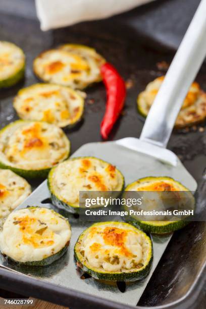 grilled courgette slices with feta on a baking tray and a spatula - fetta stockfoto's en -beelden