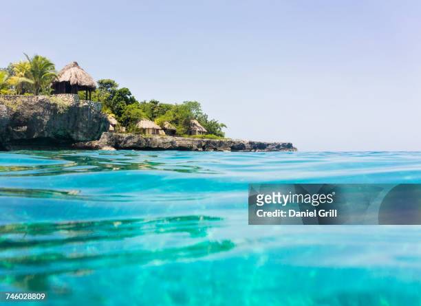 jamaica, negril, traditional huts on rocky coastline - ジャマイカ ストックフォトと画像