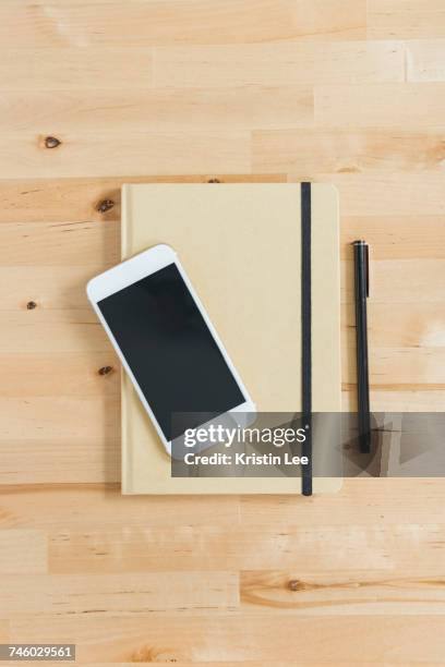 directly above view of smart phone and personal organizer and pen on wooden desk - smart communicate elevation view stockfoto's en -beelden